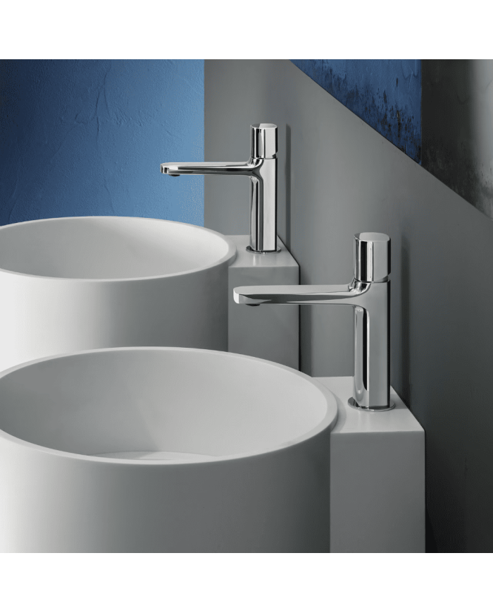 Mitigeur lavabo chromé Fantini Lamé, design moderne, bec fin, installé sur vasque ronde blanche.