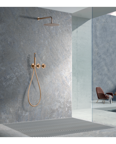 Robinetterie thermostatique encastrée en or rose brossé, mur béton brut, douchette et mitigeur apparents